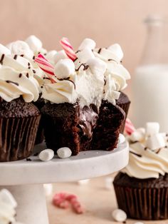 chocolate cupcakes with white frosting and candy canes on a cake stand