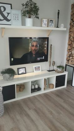 a flat screen tv mounted on a white wall in a living room with wood floors