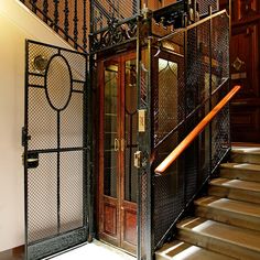 an iron gated entrance to a building with wooden stairs and wrought iron railings