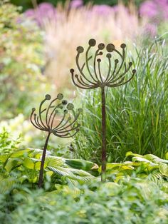 two metal flowers in the middle of a garden