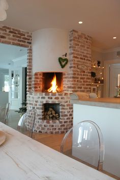 a fire place in the middle of a living room next to a kitchen and dining area