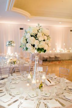 a vase filled with white flowers sitting on top of a table covered in silverware