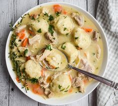 a white bowl filled with dumplings and carrots on top of a wooden table