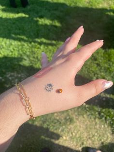 a person's hand with small tattoos on it and some grass in the background