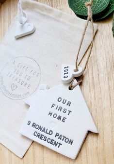 a white ceramic house ornament hanging from a string on top of a wooden table