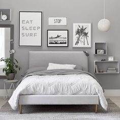 a bedroom with gray walls and pictures on the wall above the bed, along with a white rug