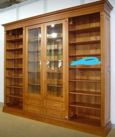 a large wooden bookcase with glass doors on the front and back sides in an empty room