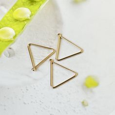 two triangle shaped earrings sitting on top of a table