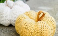 two knitted pumpkins sitting on the ground next to each other, one with a wooden handle