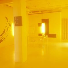 an empty room with yellow walls and white furniture in the center is illuminated by bright lights