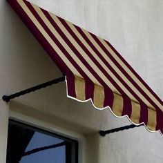 a red and white striped awning hanging from the side of a building next to a window