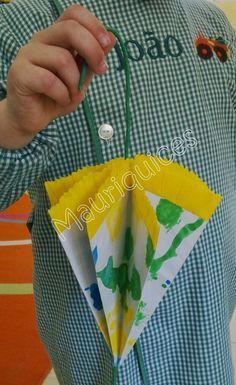 a man holding onto a yellow and green paper flower ornament in his left hand