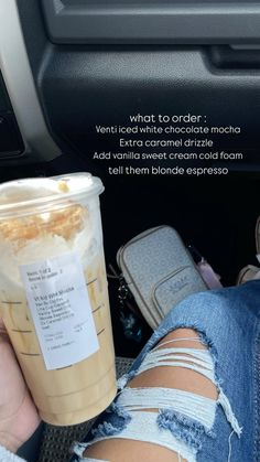 a person sitting in the back seat of a car holding a cup of coffee