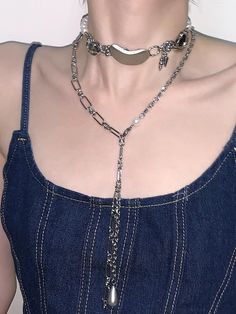 a woman wearing a blue dress and silver chain choker on her neck, with the bottom section partially covered by chains