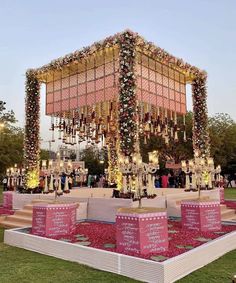 an outdoor ceremony setup with pink and white flowers on the ground, lit up by candles