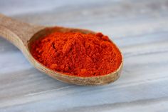 a wooden spoon filled with red powder on top of a table