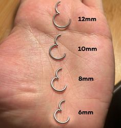 a person's hand with three different sizes of nose rings on each side of their palm