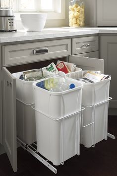 two white trash cans sitting in the middle of a kitchen