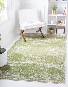 a green rug in a white room with a chair and potted plant on the floor