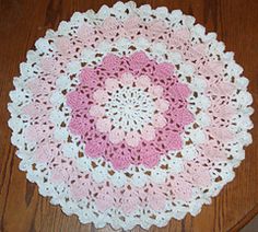 a pink and white crocheted doily on a wooden floor with the words pinit written in spanish