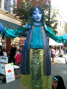 a woman dressed in blue and gold standing next to a girl with her arms outstretched