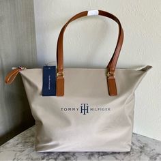 New With Tags, This Rare Tommy Hilfiger Tote Bag In A Beautiful Tan/ Beige Color Is The Perfect Everyday Bag Casual And Stylish With A Spacious Compartment And Zipper Closure To Keep Your Items Secure. This Shoulder Purse Also Includes 1 Interior Zip Pocket, 1 Interior Slip Pocket, And Features Gold Tone Hardware. Please See Last Photo For Dimensions. - Same/Next Day Shipping, Carefully Packed With Love And Care. - Top-Rated 5 Star Seller. - From A Smoke Free & Pet Free Home. - Shop 2 Or More It Tommy Hilfiger Tote Bags, Tommy Hilfiger Bag, Tommy Hilfiger Bags, Monogram Tote Bags, Suede Handbags, Monogram Tote, Black Tote, Satchel Handbags, Small Shoulder Bag