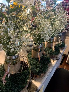 several jars filled with plants and flowers on a table