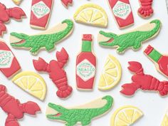 decorated cookies with red and yellow icing are arranged on a white surface, including lemons, ketchup, and alligator