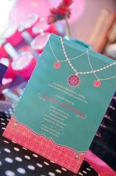 a blue and pink wedding card on top of a polka dot tablecloth with other items in the background