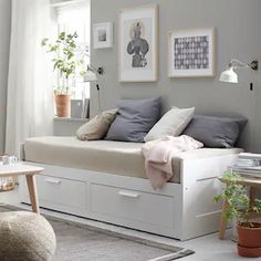 a white daybed sitting in a living room next to a chair and table with potted plants on it