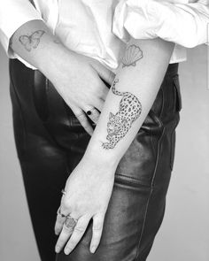 a woman's hand with a tattoo on her left arm and an animal on the wrist