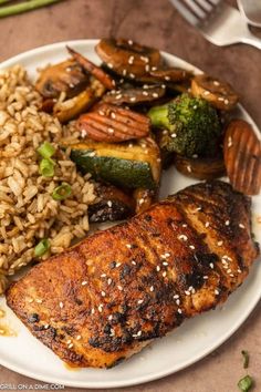 a white plate topped with meat, rice and veggies