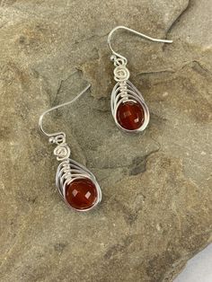 These elegant carnelian drop earrings are striking . The micro faceted surface of these genuine carnelian gemstones really catch the light and sparkles.. The color of these gemstones is burnt orange that is natural and not dyed. I chose to enhance these earrings with a woven silver wire design to let the natural beauty of the stone shine. Featuring an 8mm genuine faceted carnelian gemstone. These earrings are dainty, lightweight and perfect for everyday wear. MATERIALS * Genuine Carnelian Gemsto Bloodstone Jewelry, Carnelian Earrings, Drop Earrings Silver, Wire Design, Gemstone Drop Earrings, Carnelian Jewelry, Carnelian Stone, Dangly Earrings, Silver Drop Earrings