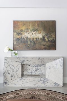 a white marble table with a painting on the wall behind it