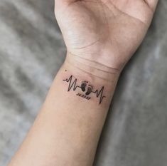 a person's wrist with a dog paw and heartbeat tattoo