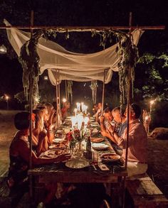 a group of people sitting at a table with food and candles in front of them