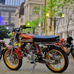 a red and yellow motorcycle parked on the side of a street next to other motorcycles