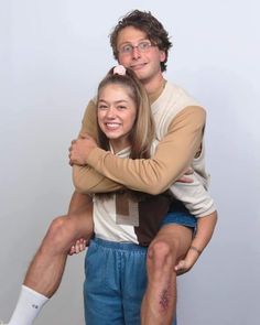 a man sitting on top of a woman's lap while they both have their arms around each other