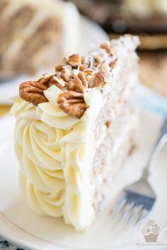 a slice of cake with white frosting and pecans on top