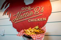 a person holding a basket full of food in front of a sign that says,'atlanta's chicken '