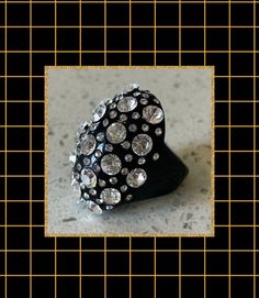 This is a gorgeous black Lucite with white rhinestone cocktail ring from the 1980's. The face of the ring measures 1 3/4 X 1 1/2" The exterior is rounded and has dozens of white rhinestones set into the surface. The ring has a matching band that measures 5/16" in the center back. The ring is in overall very good vintage condition, and a real show stopper! A gorgeous dramatic black cocktail ring for yourself or someone you love! Black Cocktail Ring, Rhinestone Ring, Black Cocktail, White Rhinestone, Matching Band, Black Rhinestone, Valentine Gift, Cocktail Ring, Cocktail Rings