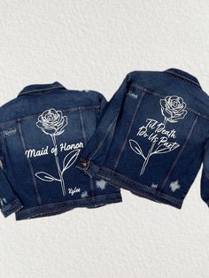 two denim jackets with embroidered roses on them, one is blue and the other has white writing