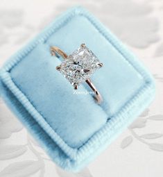 an engagement ring with a princess cut diamond in it on a white velvet box,