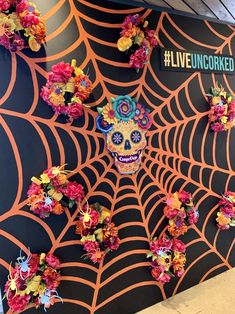 a decorated wall with flowers and a sugar skull on it's face in front of a live uncorked sign