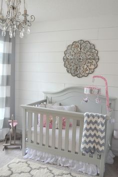 a baby's room with a crib, chandelier and rugs