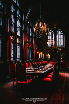 a dining room with red chairs and chandelier hanging from the ceiling in front of windows