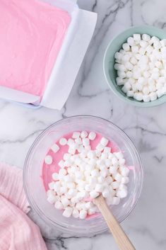 marshmallows in bowls on a marble countertop with pink and white icing