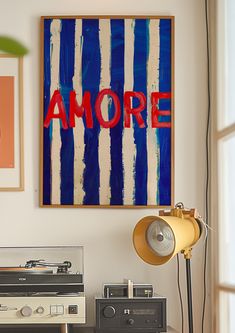 an old record player sitting on top of a table in front of a painting with the word amore