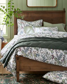 a bedroom with green walls and bedding, plants on the nightstand next to it