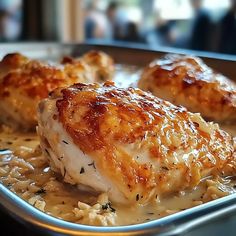 two pieces of chicken covered in gravy on top of rice